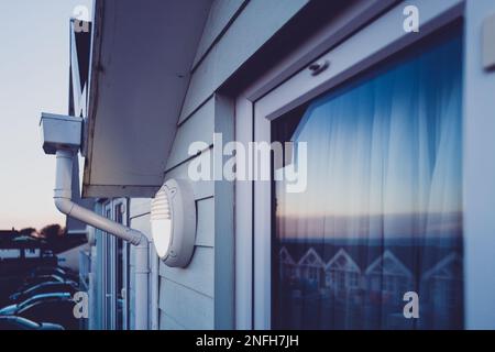 Tramonto in un resort di vacanza che mostra il sole tramontante sulle porte del patio. La spia di scarsa qualità si accende, impostata da un timer automatico. Foto Stock