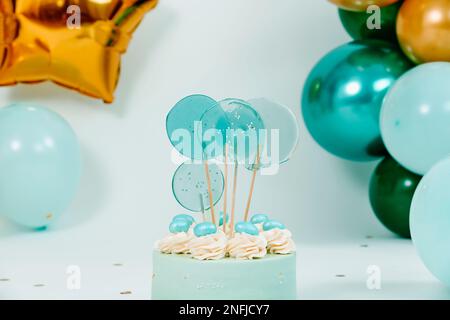 primo piano di una bella torta blu e alcuni palloncini di diversi colori e dimensioni formando una decorazione elegante per un compleanno di una festa di nozze o un bambino cak Foto Stock