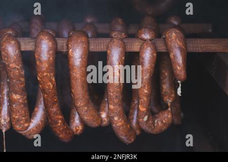 Home arrostimento di salsicce di qualità fatte in casa killer salsicce, che sono attualmente affumicati in un casale di legno a una temperatura precisa. Foto Stock