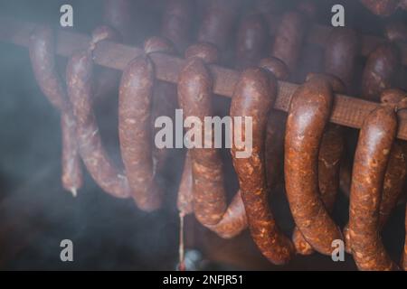 Home arrostimento di salsicce di qualità fatte in casa killer salsicce, che sono attualmente affumicati in un casale di legno a una temperatura precisa. Foto Stock