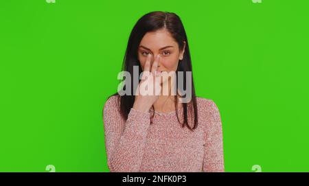 Ti sto guardando. Donna caucasica in maglione puntando i suoi occhi e la macchina fotografica, mostra che sto guardando il gesto, spiando qualcuno. Giovane adulta bella ragazza isolata da sola su sfondo chiave croma verde Foto Stock