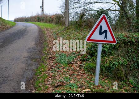 Strada in campagna e un segno di diverse svolte. Segnale di avvertimento per il percorso di avvolgimento. Foto Stock