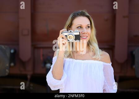 Vista frontale di una donna di mezza età sorridente con una vecchia macchina fotografica e guardando da parte Foto Stock