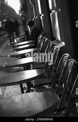 Scena monocromatica Street di tavoli e sedie fuori Un caffè con Una donna bere Un caffè in primavera Parigi Francia Foto Stock