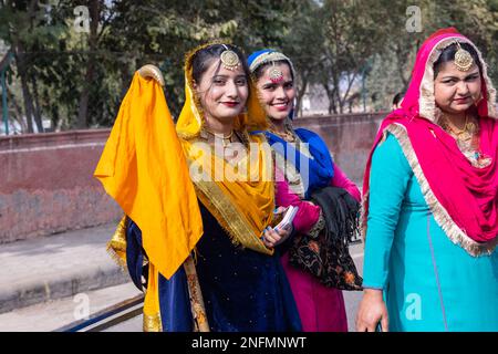 Punjabi Bhangra, Ritratto di giovane donna sikh in tradizionale abito colorato punjabi e turbante che esegue bhangra dance con sorriso nel festival del cammello. Foto Stock