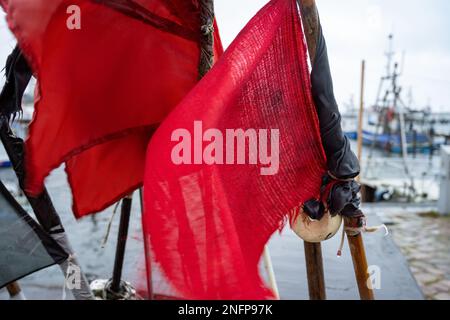 Sassnitz, Germania. 17th Feb, 2023. Bandiere rosse e nere per marcare le reti che sbattono nel vento nel porto. Secondo le previsioni del servizio meteorologico tedesco (DWD), sono previste squall con velocità del vento comprese tra 60 e 80 chilometri all'ora. Credit: Stefan Sauer/dpa/Alamy Live News Foto Stock