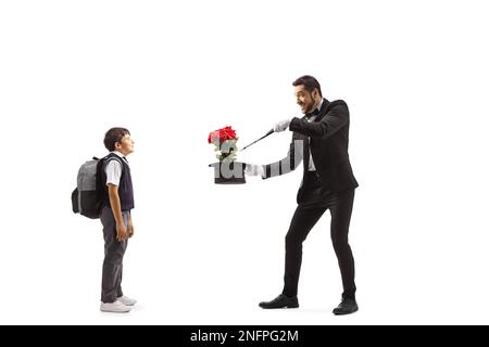 Ragazzo che guarda un mago che esegue un trucco con cappello e rose isolate su sfondo bianco Foto Stock