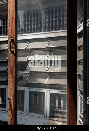 Bangkok, Thailandia - 09 febbraio 2023 - Vista attraverso una vecchia finestra dell'antico vecchio edificio su antiche finestre di acciaio tendone l'altro lato del buil Foto Stock