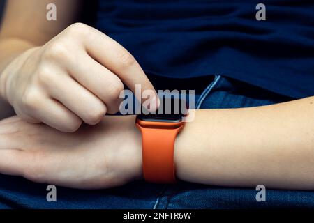 Mano maschio irriconoscibile con smartwatch Bluetooth rosso, tecnologia gadget elettronica. Controllo della frequenza cardiaca, del tempo e dei messaggi di chiamata, fitness tracker Foto Stock