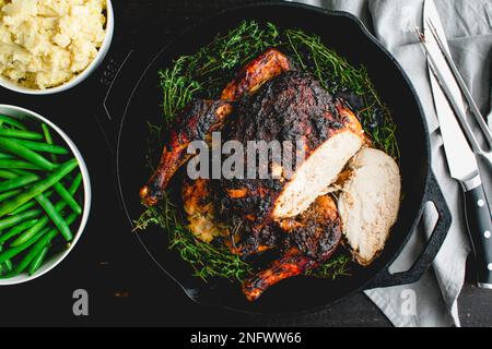 Pollo arrosto al burro di mele a fette con coltello e forchetta: Arrosto di pollo in una padella di ghisa con purè di patate e fagioli verdi Foto Stock