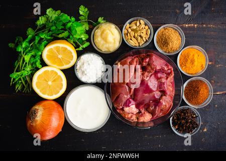Curry di fegato di pollo ingredienti su uno sfondo di legno scuro: Fegati di pollo crudi, spezie indiane, e altri ingredienti su un tavolo di legno Foto Stock