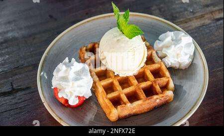 un'immagine di un waffle appena preparato accompagnato da un primo piano con panna montata e gelato Foto Stock