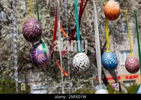 Le uova dipinte pendono dai rami dell'albero di Pasqua. Il fuoco è su un uovo giallo dipinto dai bambini a mano. Foto di alta qualità Foto Stock