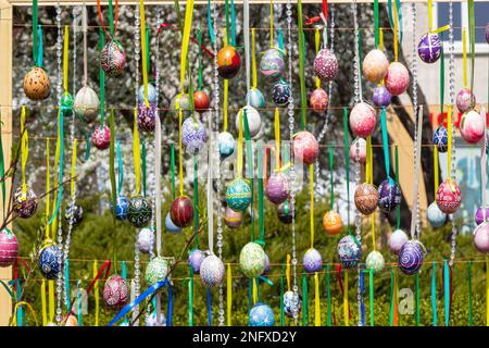 Le uova dipinte pendono dai rami dell'albero di Pasqua. Il fuoco è su un uovo giallo dipinto dai bambini a mano. Foto di alta qualità Foto Stock