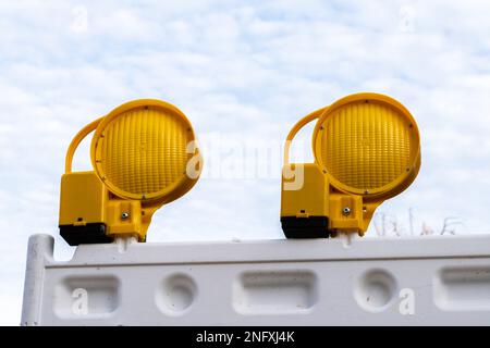 Due lampeggiatori di emergenza gialli situati su un pannello di plastica bianco. Primo piano contro un cielo nuvoloso. Foto Stock