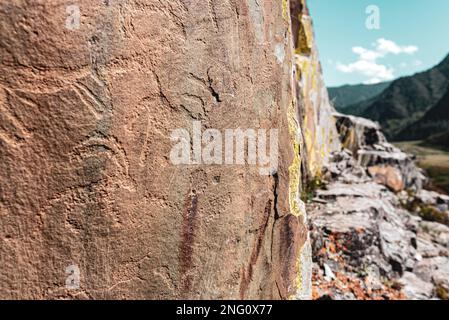 Incisioni rupestri di antichi animali sulle pietre dietro il panorama delle montagne Altai in Siberia. Foto Stock