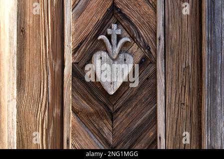 vecchio hart in legno con disegno a croce scolpito sulla parete del santuario lungo la strada Foto Stock