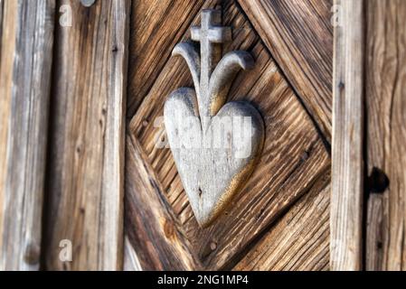 vecchio hart in legno con disegno a croce scolpito sulla parete del santuario lungo la strada Foto Stock