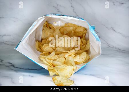 Sacchetto di patatine posate sul bancone con schegge che cadono Foto Stock