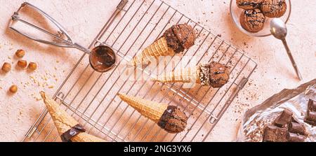 Gelato al cioccolato su una rastrelliera metallica con paletta in acciaio inox, banner orizzontale. Piano di giacitura, vista dall'alto Foto Stock