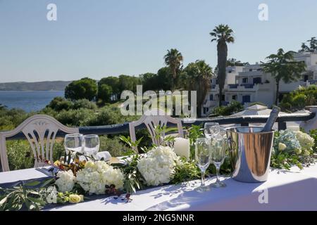 Elegante tavolo decorato con fiori bianchi e foglie verdi centrotavola e panno di lino bianco per un fidanzato, ricevimento di nozze o altro Foto Stock