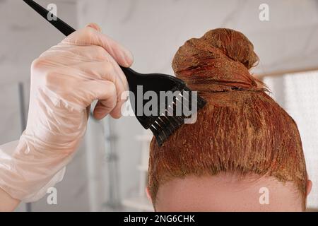 Giovane donna tintura i capelli con henné in casa, primo piano Foto Stock