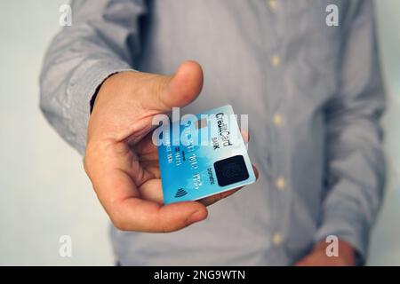 Primo piano di un giovane uomo che utilizza la carta biometrica con impronte digitali per effettuare il pagamento online senza un codice PIN. L'uomo d'affari paga con carta di credito con scann biometrico Foto Stock