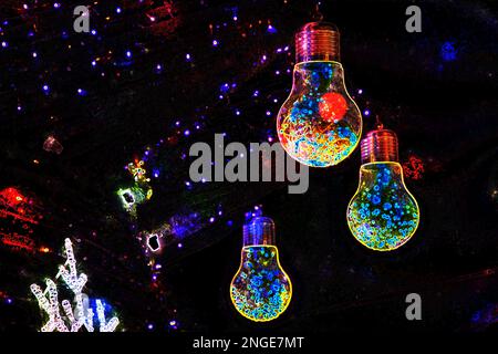 Ghirlanda di Natale di lampadine sugli alberi di Natale in effetti neon in colori scuri, il design di Capodanno e le vacanze Foto Stock