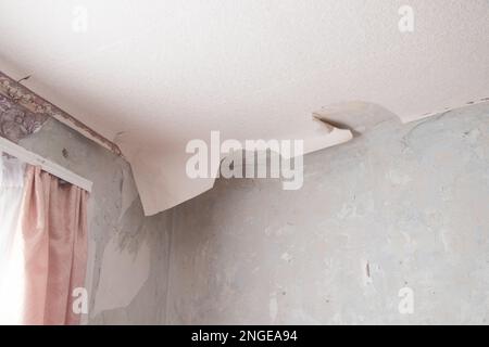 rimozione della vecchia carta da parati dalle pareti in una stanza di un edificio residenziale, ristrutturazione di un appartamento Foto Stock