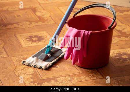 un secchio di guanti e un mop sul pavimento in camera da letto, la pulizia dell'appartamento Foto Stock