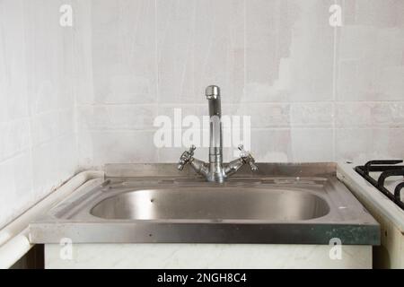 cucina vecchio lavabo e rubinetto in cucina primo piano sullo sfondo di piastrelle bianche Foto Stock