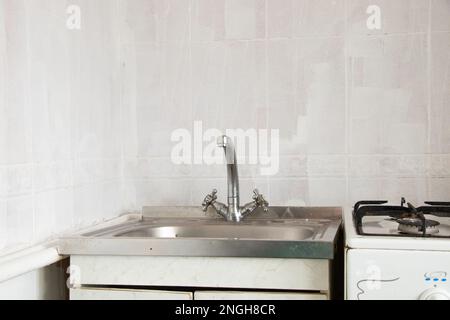 cucina vecchio lavabo e rubinetto in cucina primo piano sullo sfondo di piastrelle bianche Foto Stock