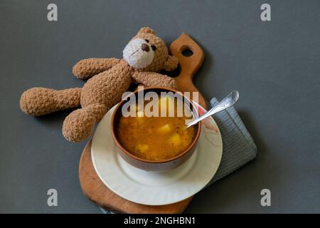 orsacchiotto e un piatto di zuppa accanto ad un buio Foto Stock