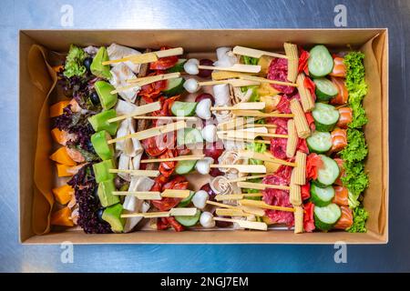 Scatola grande con spuntini su bastoncini consegnata per il servizio di catering in loco. Deliziosi antipasti naturali per la festa. Ripresa diretta con stile flat lay Foto Stock