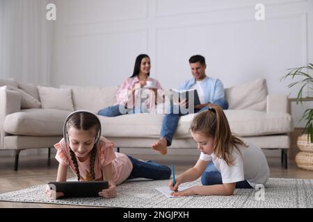 Famiglia nel soggiorno con comodo divano, focalizzazione sui bambini Foto Stock