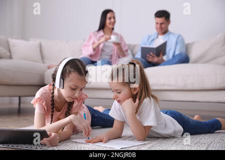 Famiglia nel soggiorno con comodo divano, focalizzazione sui bambini Foto Stock