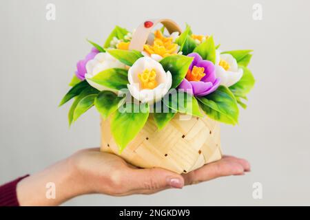 Un piccolo cesto realizzato in impiallacciatura con croci e narcisi di sapone fatto a mano di una donna. Foto Stock