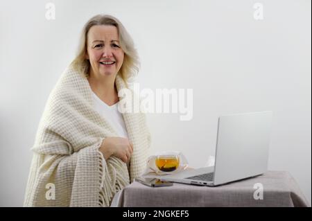 Donna che guarda nella cornice ridendo su uno sfondo bianco giovane donna congelata con tazza di tè al lavoro a casa. Foto di alta qualità Foto Stock