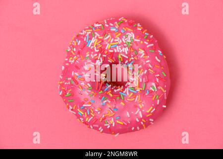 Ciambella con glassa rosa e zucchero multicolore spasles.on sfondo rosa Foto Stock