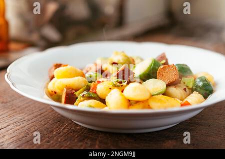 Piastra con gnocchi, servita con i cavoletti di Bruxelles e vegan hot dog pezzi. Foto Stock