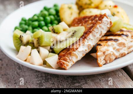 Kiwi e salsa di pere, serviti con tempeh, piselli e patate Foto Stock