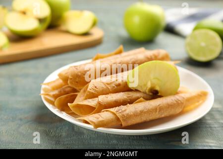 Composizione con deliziosi rotoli di frutta in pelle e mela su tavola di legno blu Foto Stock