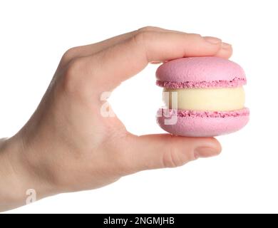 Donna che tiene delizioso macaron rosa su sfondo bianco, primo piano Foto Stock