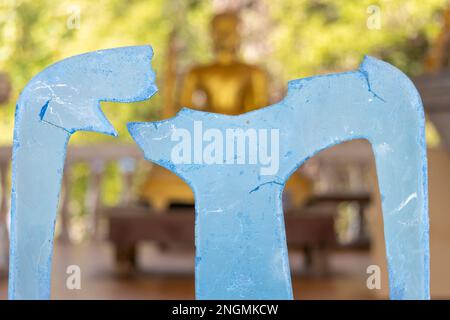 Una sedia di plastica rotta in un tempio buddista, Thailandia Foto Stock