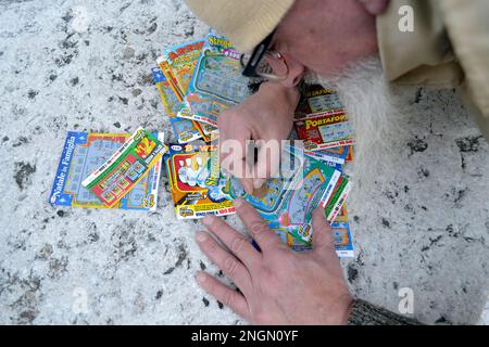 Un uomo che graffia una scheda di graffio della lotteria - concetto di dipendenza di gioco Foto Stock