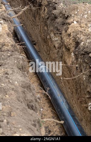 Tubo fognario in plastica in trincea per la posa di un sistema fognario esterno in un cantiere. Foto Stock