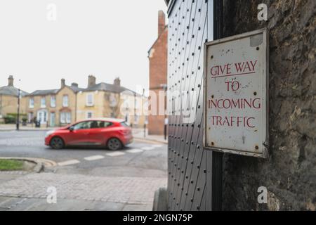 Poco profonda messa a fuoco di un imminente segnale di traffico senato l'ingresso di una vecchia scuola privata inglese. Oltre il cancello c'è una strada a senso unico. Foto Stock