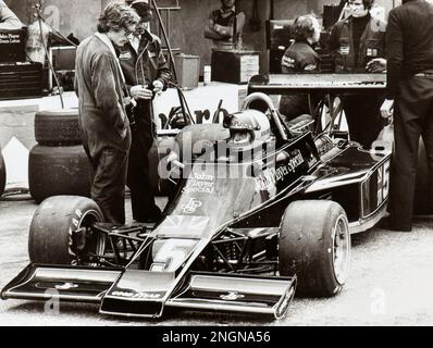 Il pilota di gara MARIO ANDRETTI ha seduto nel suo John Player Special Lotus al box prima di una gara di Formula 1 Foto Stock