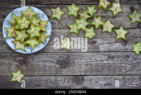 Frutta carambola tagliata su fondo di legno. Fette di Starfruit su un piatto decorativo. Vista dall'alto. Composizione di posa piatta. Foto Stock