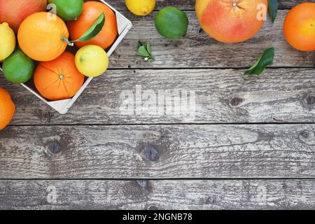 Cornice superiore di agrumi o bordo su sfondo di legno. Arance, limoni, pompelmi e lime con foglie su un tavolo di legno. Spazio di copia. Vista da circa Foto Stock